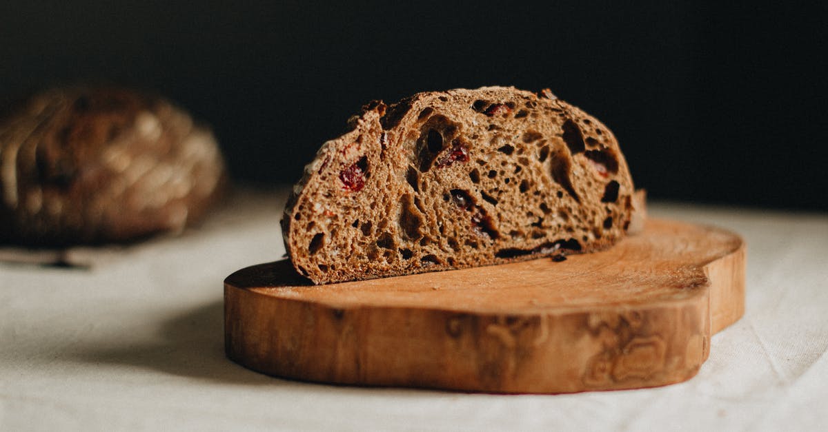 100% Whole wheat sourdough bread method - Slice of tasty homemade sourdough cranberry whole wheat bread placed on wooden chopping board on table against black blurred background