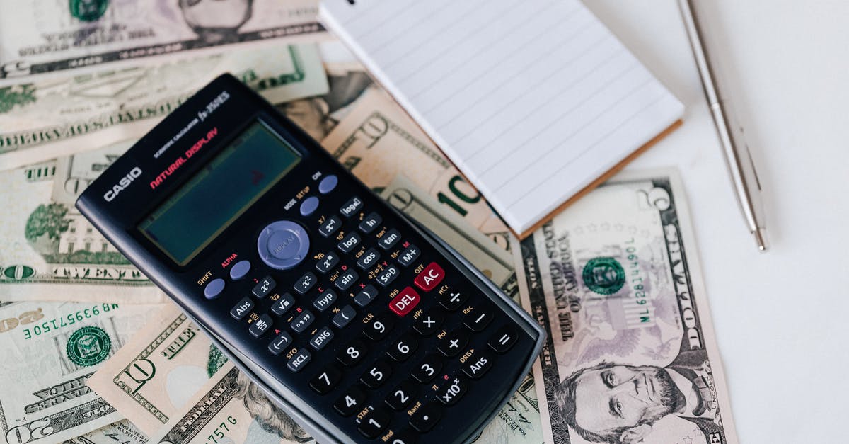 12 count versus 24 count cupcake pan - From above electronic calculator and notepad placed over United States dollar bills together with metallic pen for budget planning and calculation