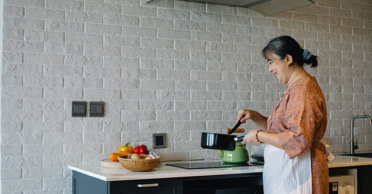 'Sweet milk' substitute in an old recipe - Side view of elderly female in apron standing near stove and holding pan while preparing lunch at home