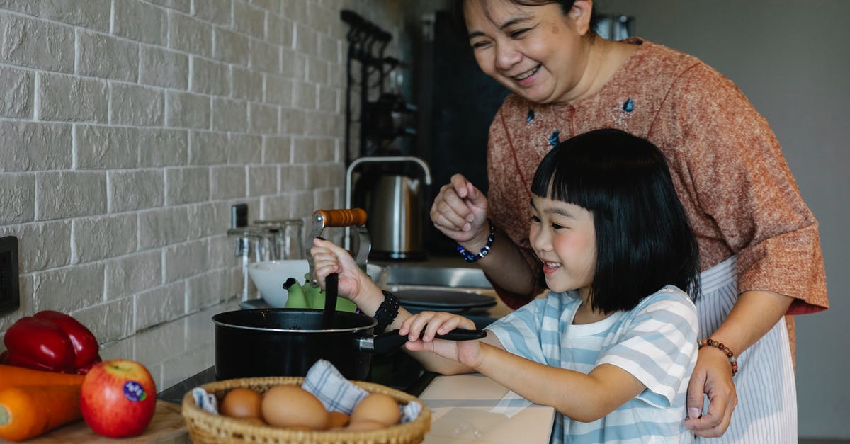 3+ egg omelette in a pan - Asian woman with granddaughter preparing food