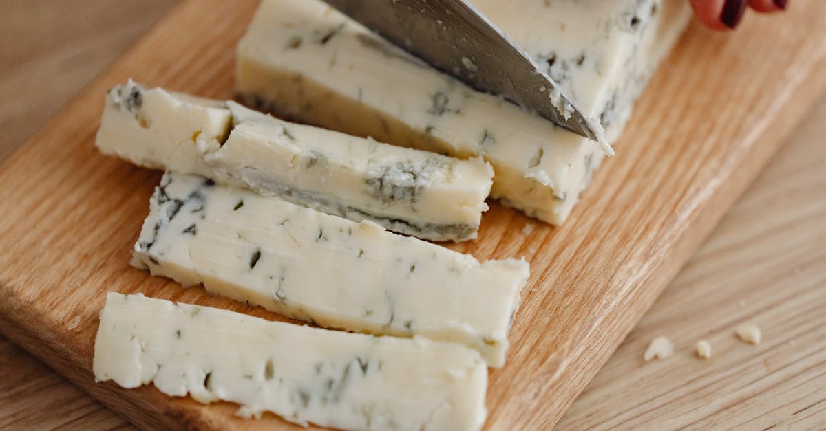 40lb.round of opened grana padano cheese - A Person Cutting Gorgonzola Cheese