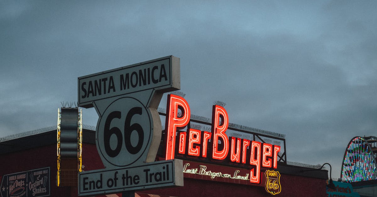 A burger made from pastrami - Low angle of road sign with Route 66 End of the Trail inscription located near fast food restaurant against cloudy evening sky on Santa Monica Beach