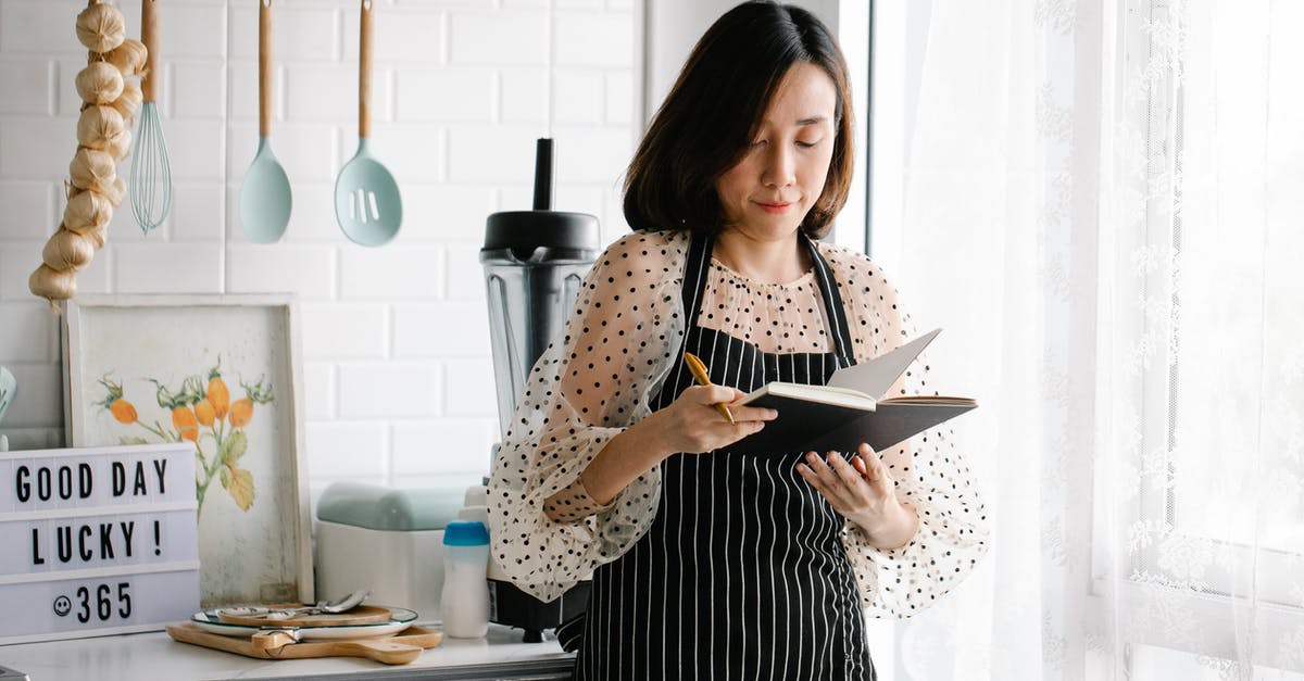 A great book with recipes for Tapas - A Woman in an Apron Holding a Journal in a Kitchen