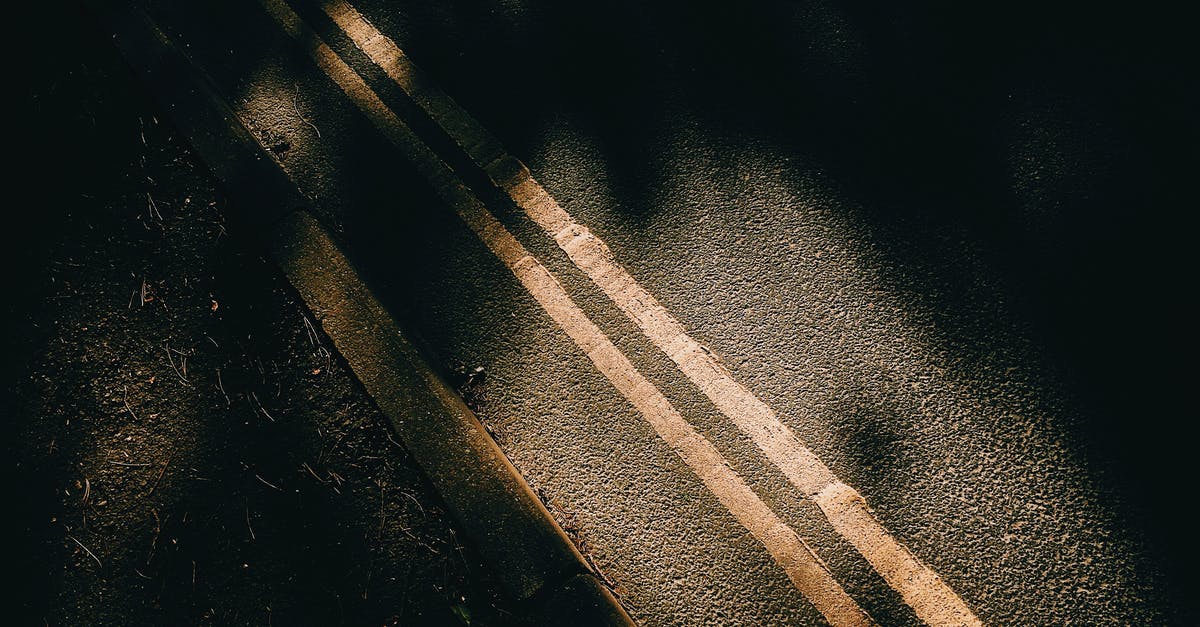 A simple way to make crushed ice? - From above of asphalt roadway with yellow marking lines with dark shades near ground in sunny day in street