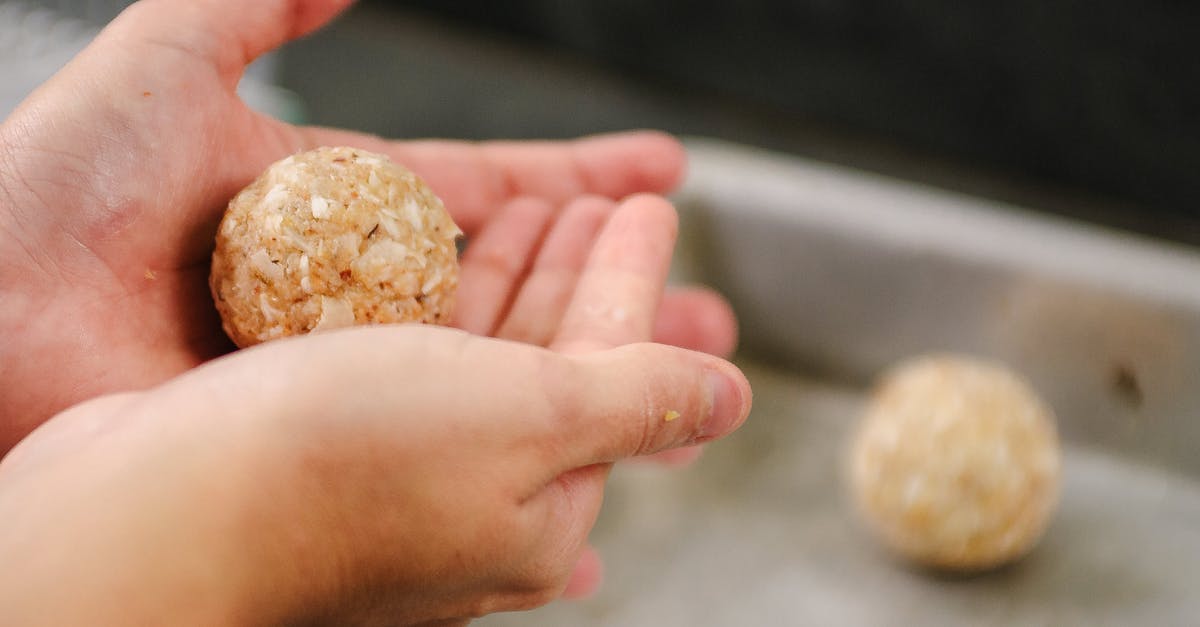 A substitution for pork in Swedish meatballs - Crop faceless person showing delicious round meatballs in kitchen while cooking at home