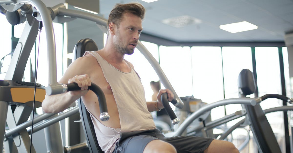 About 'sharpening"; do you PUSH OR PULL the blade across the stone? - Focused adult male athlete in sportswear using weight machine for arms and chest during workout in modern spacious fitness center in morning