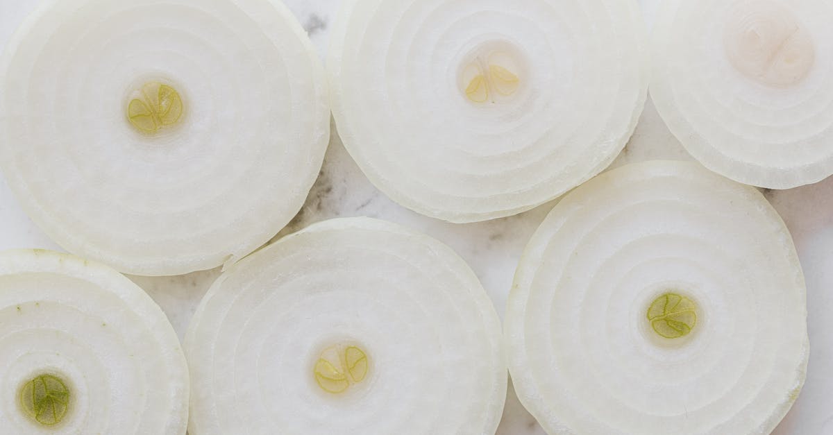 Achieve butter-like aroma in a vegan recipe - Top view closeup of ripe organic yellow peeled onion cut into rings and placed on white marble tabletop