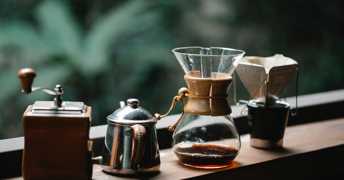 Achieving perfection via manual drip-brew coffee method - Chemex coffeemaker with cup placed on terrace with metal kettle and hand grinder