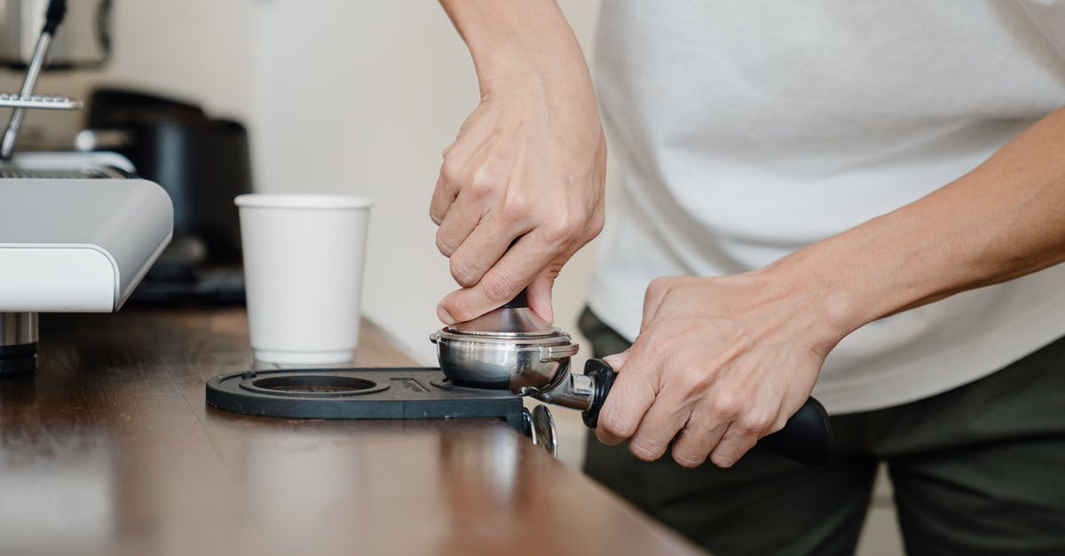 Achieving perfection via manual drip-brew coffee method - Crop barista preparing coffee pod in holder with tamper