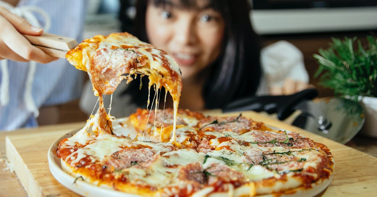 Adding butter to pizza recipe - Women taking piece of pizza with tomatoes and cheese