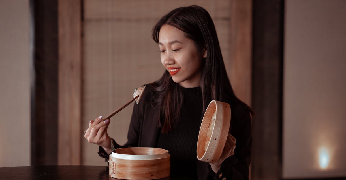 Adding chili powder to a dish makes it dark black - Woman in Black Jacket Holding Chopsticks with Dumplings