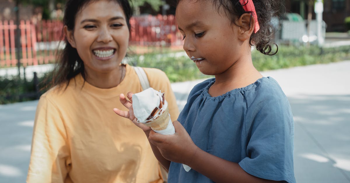 Adding melted butter to cold milk in baking - Cheerful Asian mother looking at daughter eating ice cream