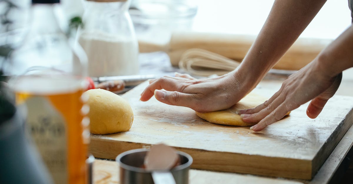 adding peanut butter to a recipe - Female hands kneading fresh dough on wooden chopping board with flour in kitchen