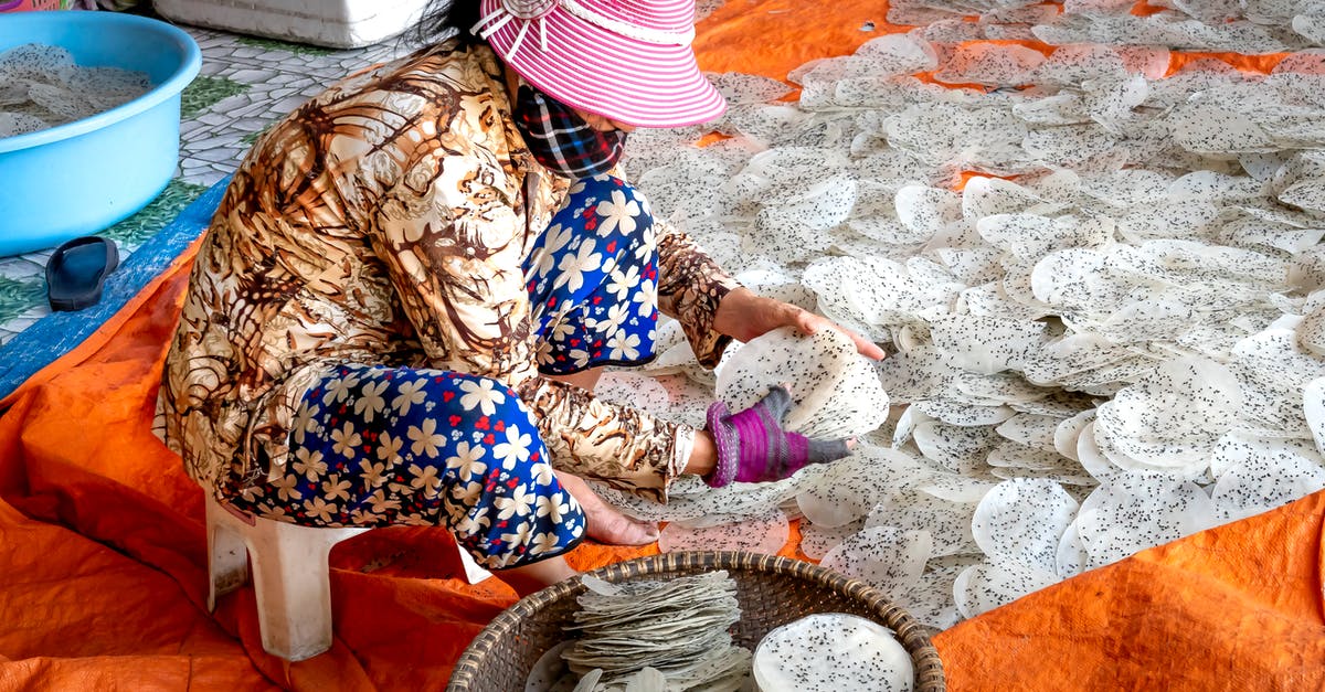 Adding raw chia seeds to baked goods? - Side view of anonymous ethnic female in panama hat preparing rice sheets with chia seeds on textile