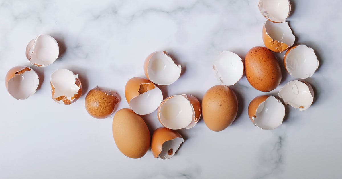 Adding raw chicken to a meal that is being reheated - Top view of pile of brown shells and whole eggs scattered on marble table in kitchen on sunny day