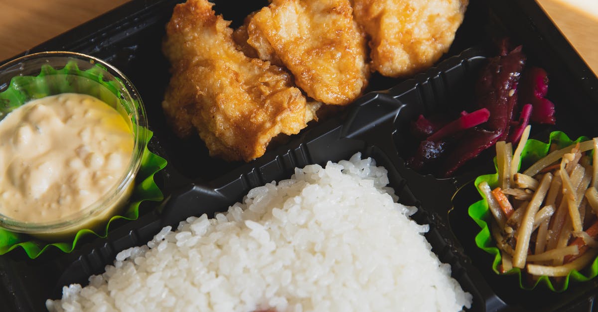 Adding sauce without microwaving the chicken - From above of plastic container with fried chicken and rice with sauce near sauce and sliced vegetables