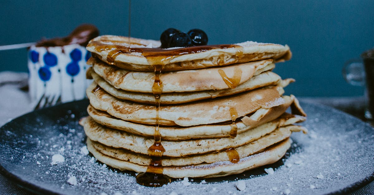 Adding sugar and honey to sourdough culture - Pile of tasty homemade golden pancakes decorated with fresh blueberries and honey on plate with icing sugar