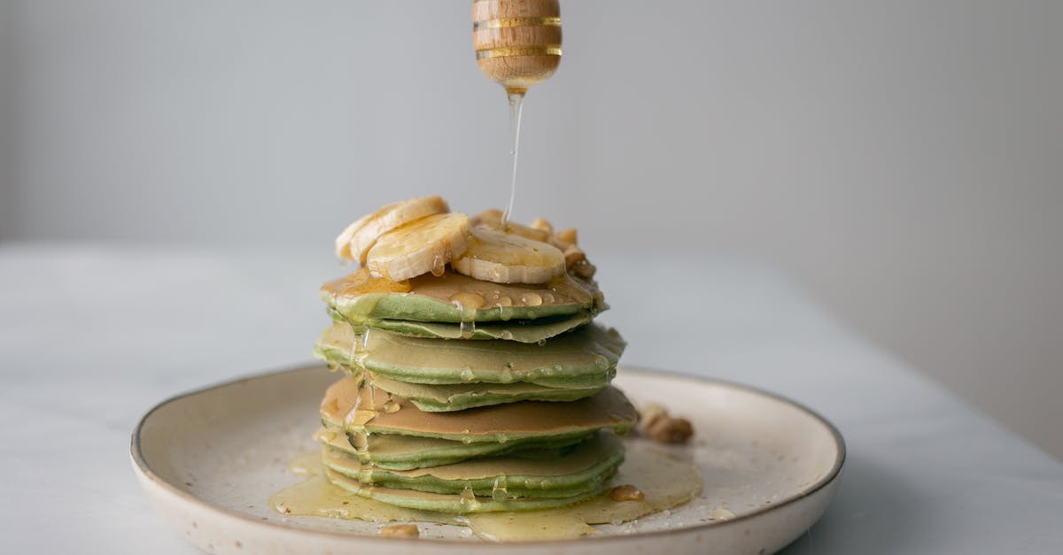 Adding sugar and honey to sourdough culture - Tasty pancakes with fresh bananas served on plate and table on white blurred background