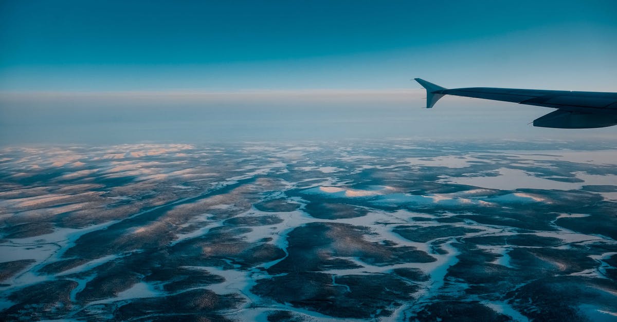 Air dehydrating ambient air temperature? - Wing of airplane flying in blue cloudless sky with skyline above vast terrain covered with snow in nature on winter day