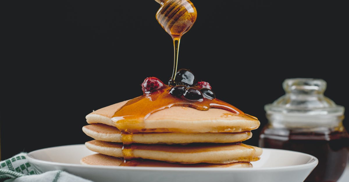 Air fried sweet potatoes have black dots on them - Close-up View of Honey Spoon above Pancakes