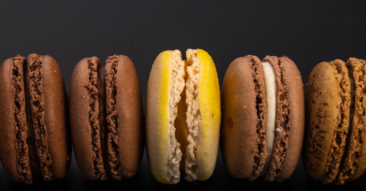 Alternative for shake and bake? - Top view of yummy sweet macaroons with cream arranged in row on black background