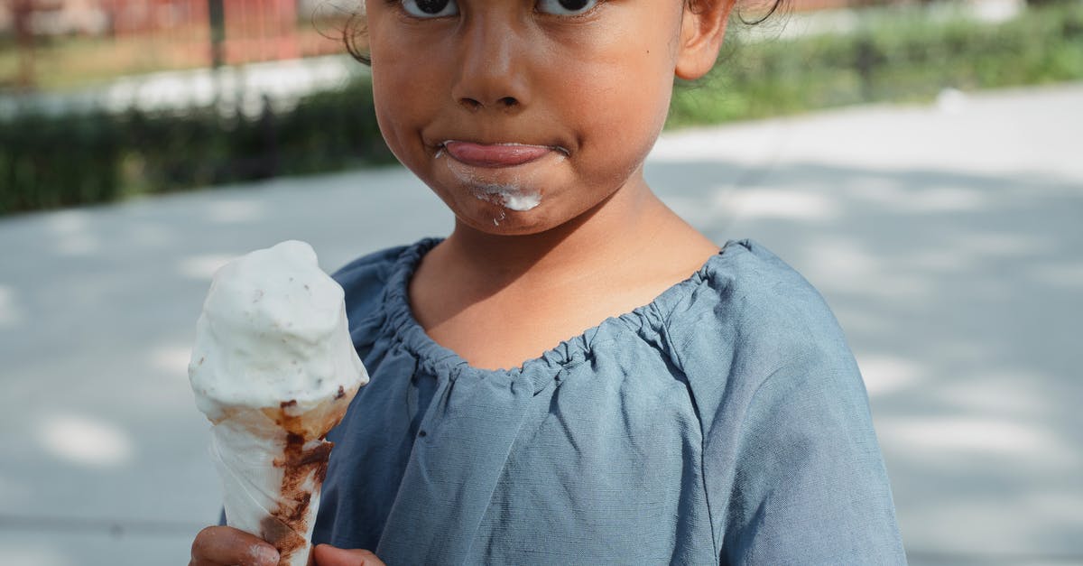 Am I supposed to eat frozen cherries directly - Crop adorable little Asian girl in casual clothes eating ice cream and looking at camera