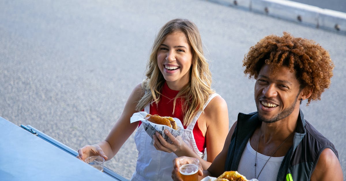 American cheese availability and utility - Delighted multiethnic couple with drinks and food on street