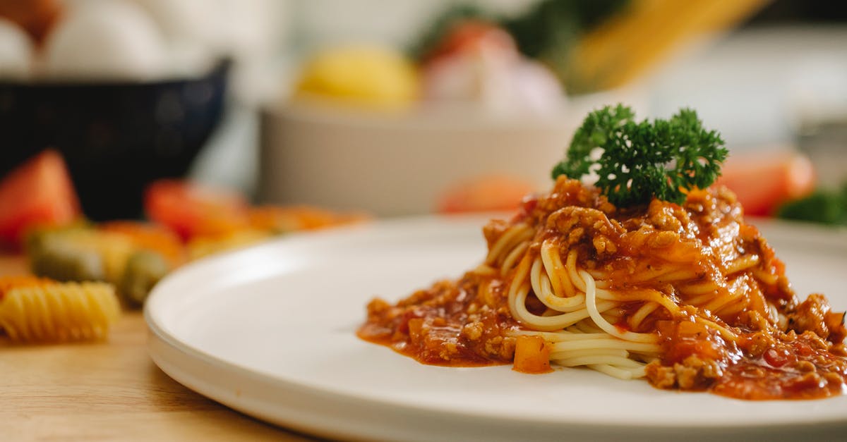 American recipe using 'a can of tomato sauce' - Delicious yummy spaghetti pasta with Bolognese sauce garnished with parsley and served on table in light kitchen