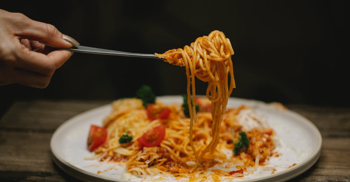 American recipe using 'a can of tomato sauce' - Crop anonymous female with fork enjoying yummy Bolognese pasta garnished with cherry tomatoes and parsley