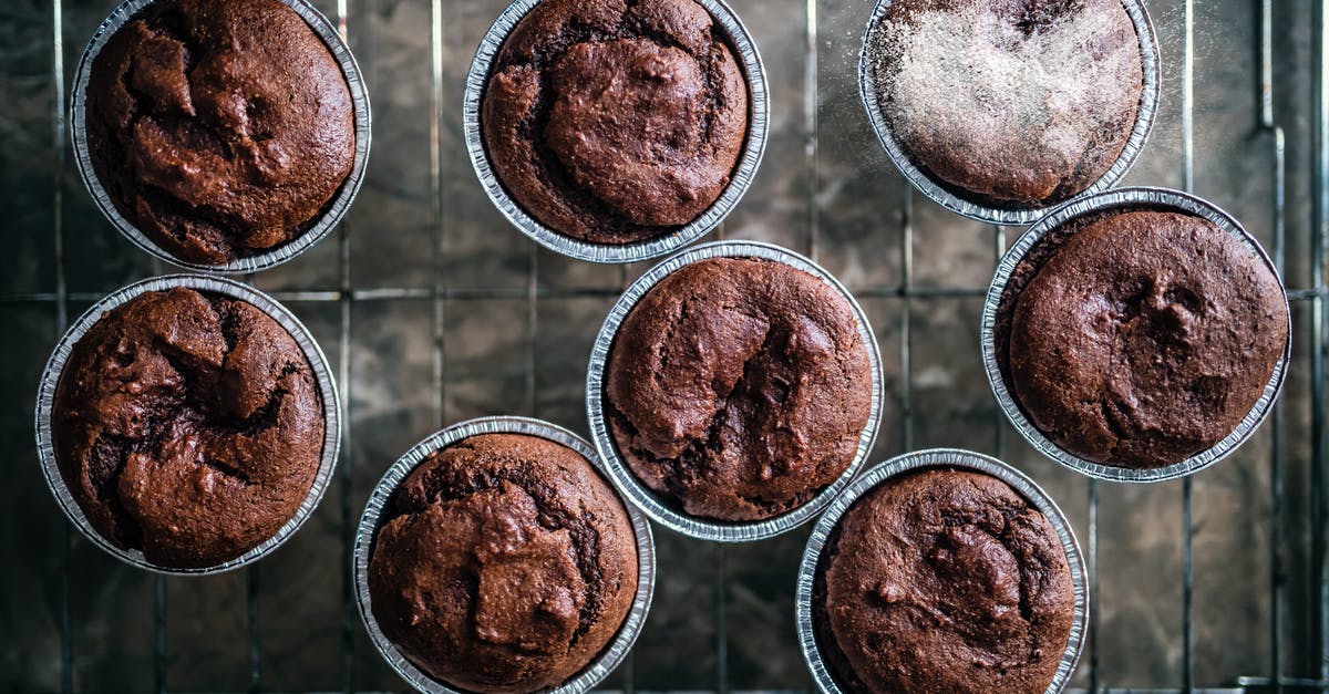 Amount of baking powder in a muffin recipe - Top view of freshly baked brown chocolate muffins placed on metal tray in baking cups