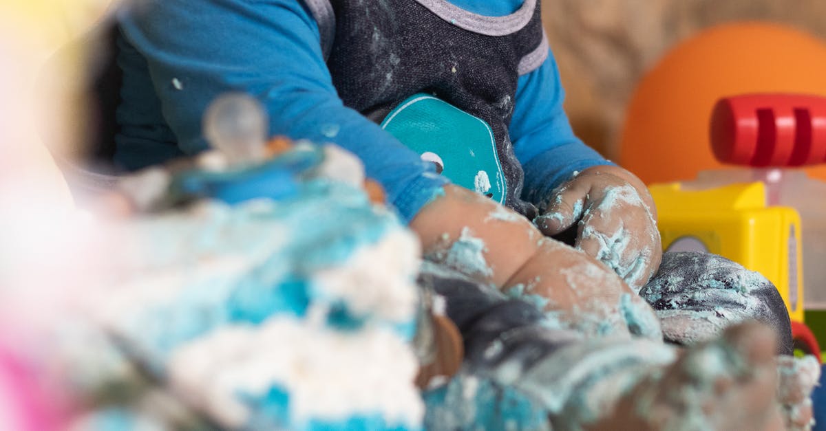 Angel Food Cake: crushed pineapple instead of sugar? - Unrecognizable barefoot toddler in comfortable wear playing with light blue sugar cream for festive cake