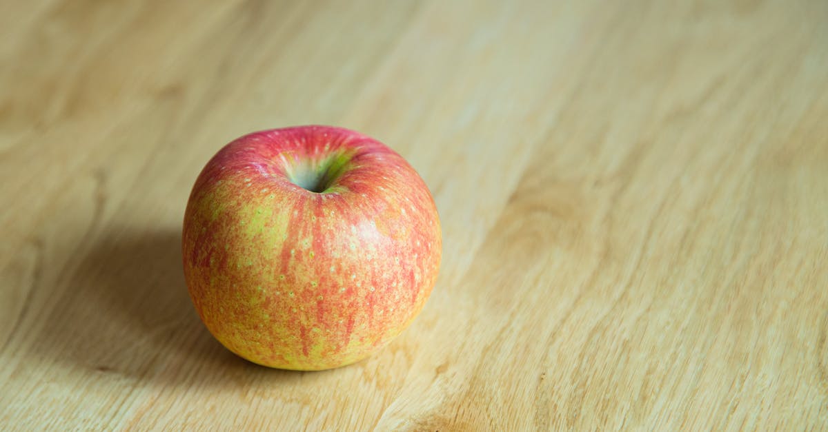 Apple pie: peel or not? - From above of delicious whole juicy apple with red and yellow peel on desk