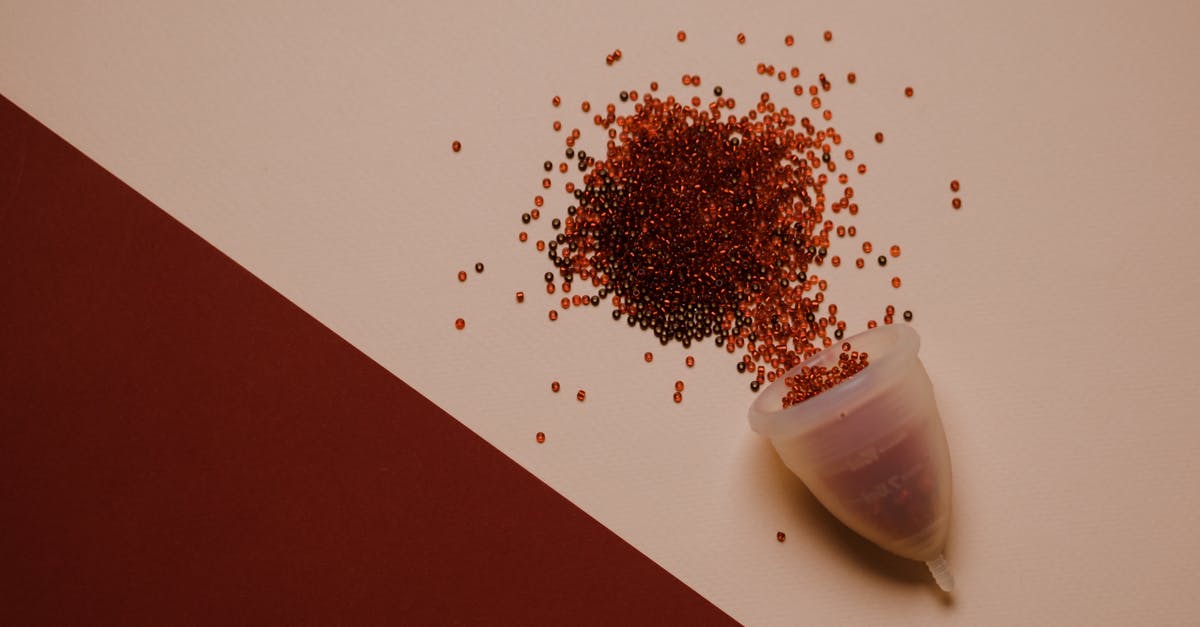 Are Blood Oranges actually that red - Top view of silicone menstrual cup with red beads scattered on pink surface