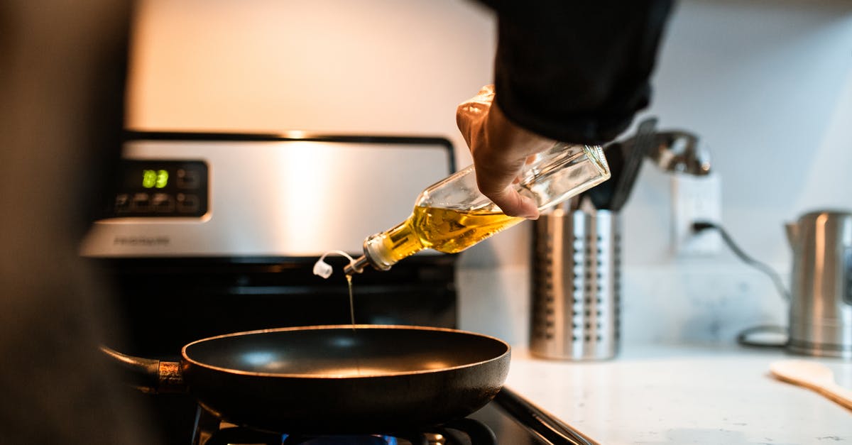 Are chilies in olive oil dangerous? - Back view crop unrecognizable person pouring olive or sunflower oil into frying pan placed on stove in domestic kitchen