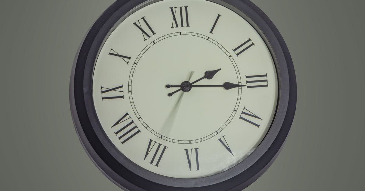 Are cooking show minutes really minutes? - Round black mechanical clock with Roman numerals hanging on gray wall