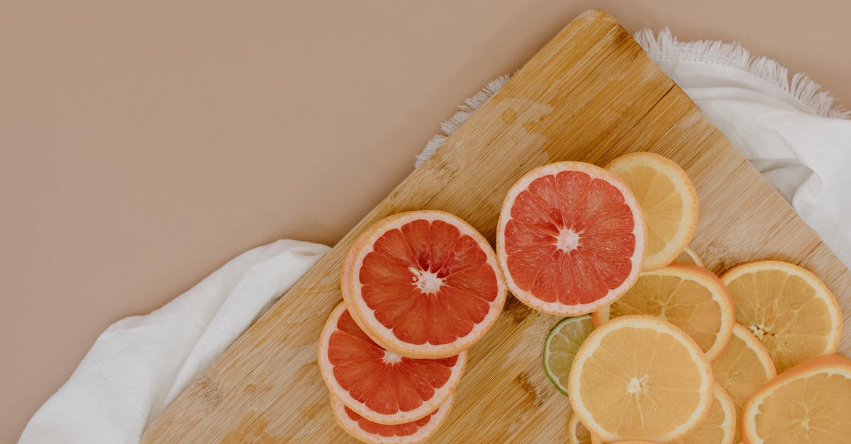 Are Gem Squash Edible After the Green Rind Turns Yellow/Orange? - Top view of wooden cutting board with sliced oranges and red grapefruits near green limes and yellow lemons on white textile on beige surface in light studio