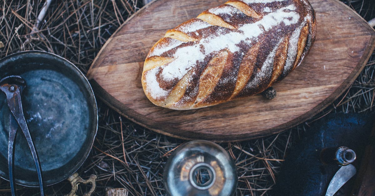 Are Non-Stick Bread Pans Destined to Fail? - From above of fresh homemade bread on wooden cutting board near glass bottle and old pan with plier placed on grassy lawn in daylight