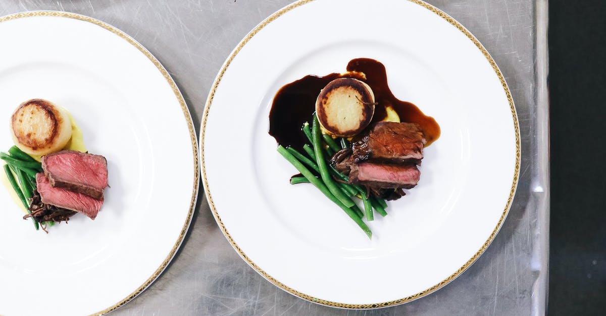 Are roasted bean flours edible as is? - Top view of cut roasted meat near pan fried polenta and green beans with sauce on white plates on table in light restaurant