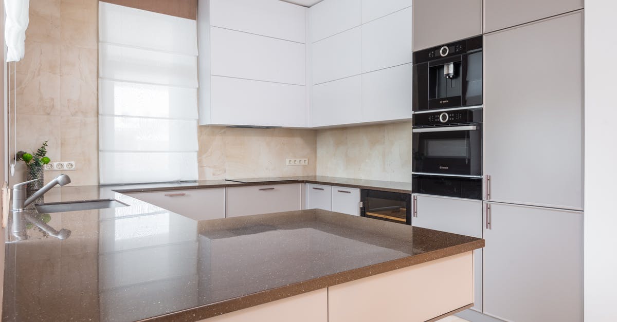 Are stainless steel frypans oven safe? - Contemporary kitchen with white and beige cupboards and built in appliances and cutting table laid with stone countertop and metal sink