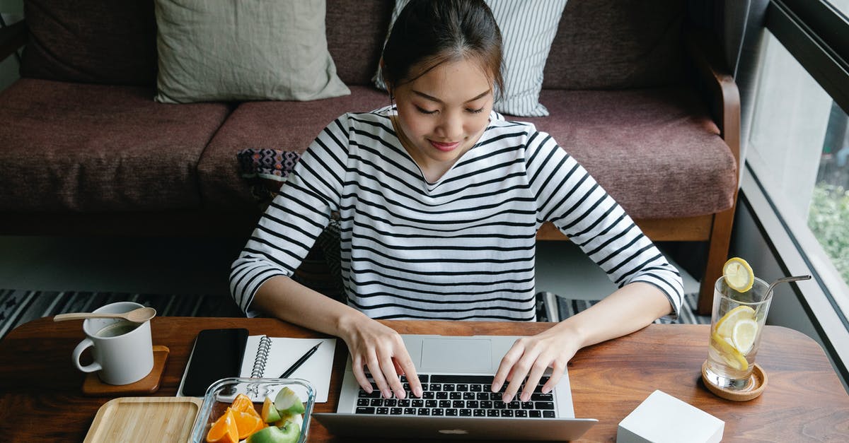 Are there benefits to using a lemon squeezer? - Asian freelancer typing on laptop at table with lemonade indoors