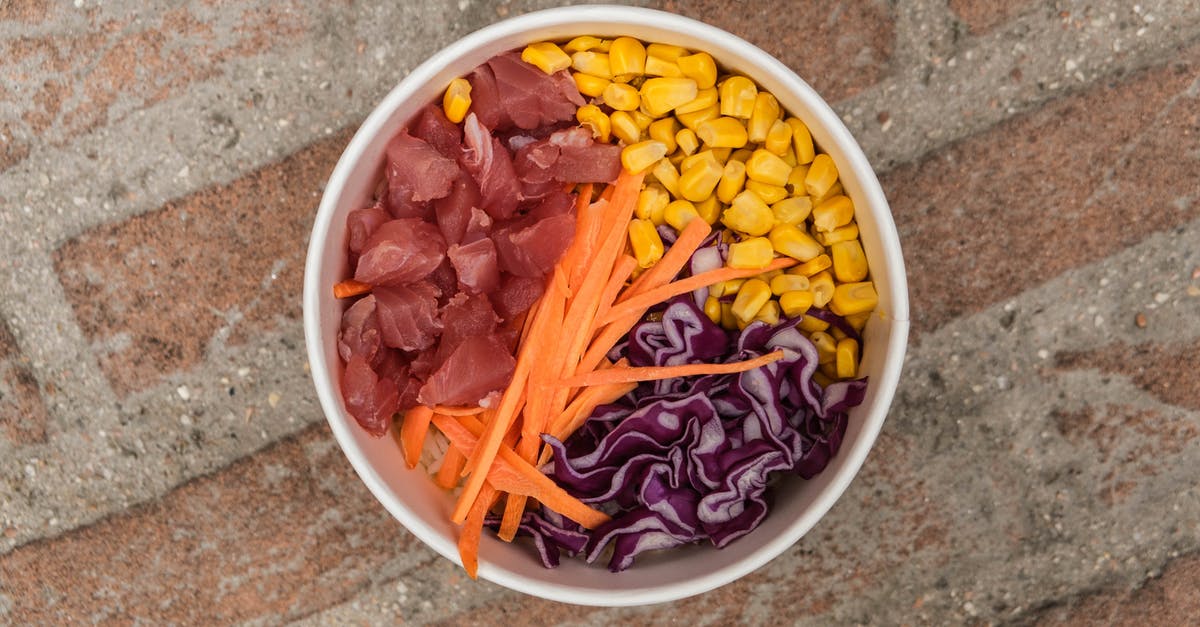 Are there culinary applications for carrot tops/greens? - Top view of bowl with carrot meat and fresh corn placed on rough brick surface