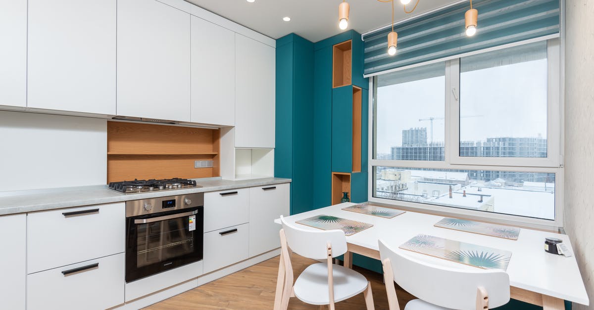 Are there gas ovens that come with a thermometer? - Cabinet with gas stove and oven against placemats on table under lights in modern apartment