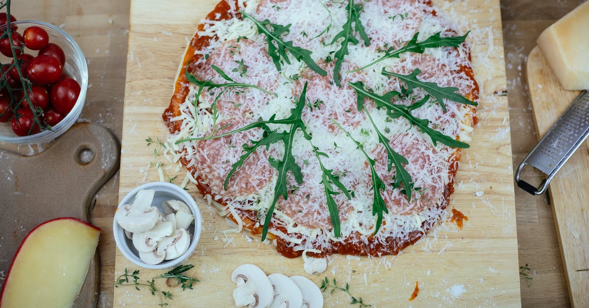 Are there substitutes for Parmesan without the aged cheese flavor? - Uncooked pizza with herbs on kitchen table Are there substitutes for Parmesan without the aged cheese flavor? - Uncooked pizza with herbs on kitchen table
