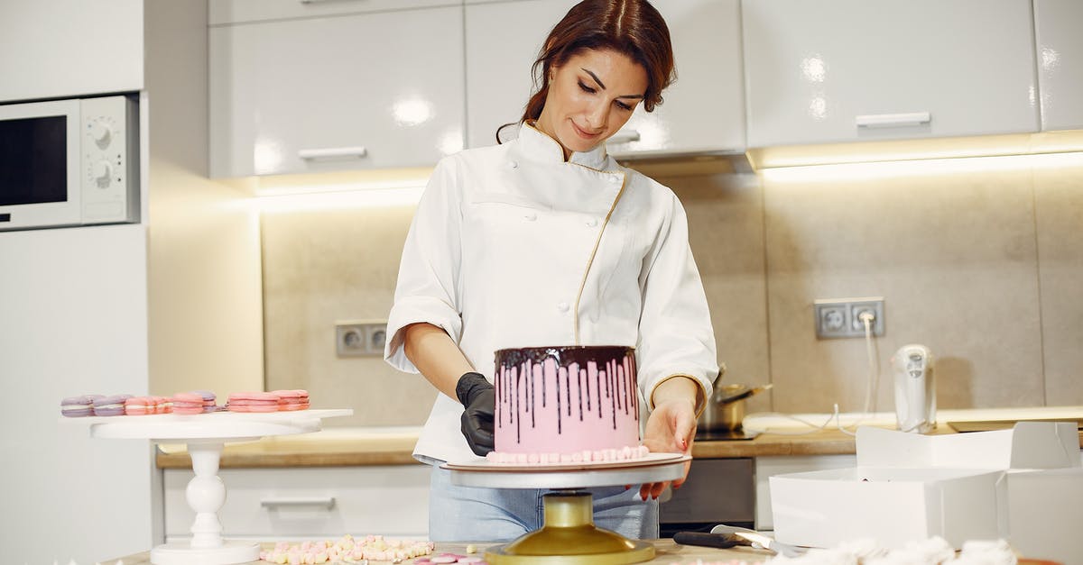 at what temperature should apple-choco pie be prepared? - From below of concentrated female pastry cook in uniform garnishing pink cake with marshmallows among confectionery items in kitchen