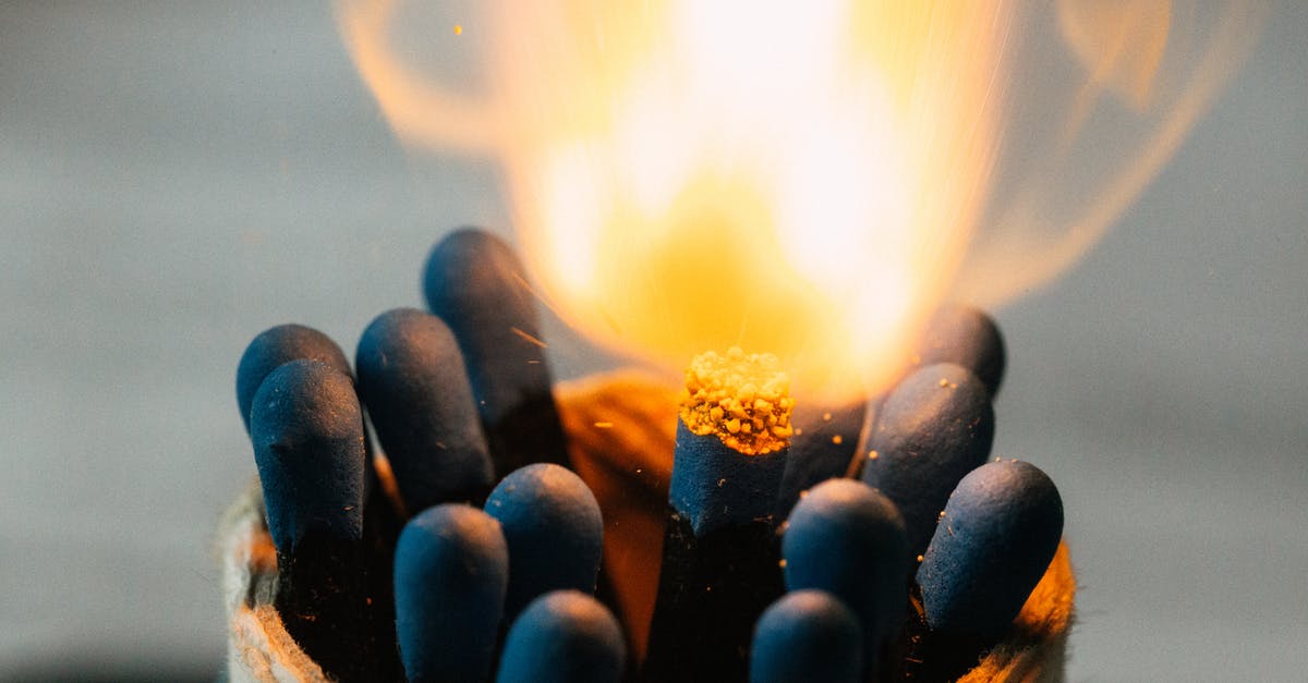 At what temperature should I simmer bolognese to avoid burning? - Closeup of burning fire on match head among pile of black matches in jar on blurred background