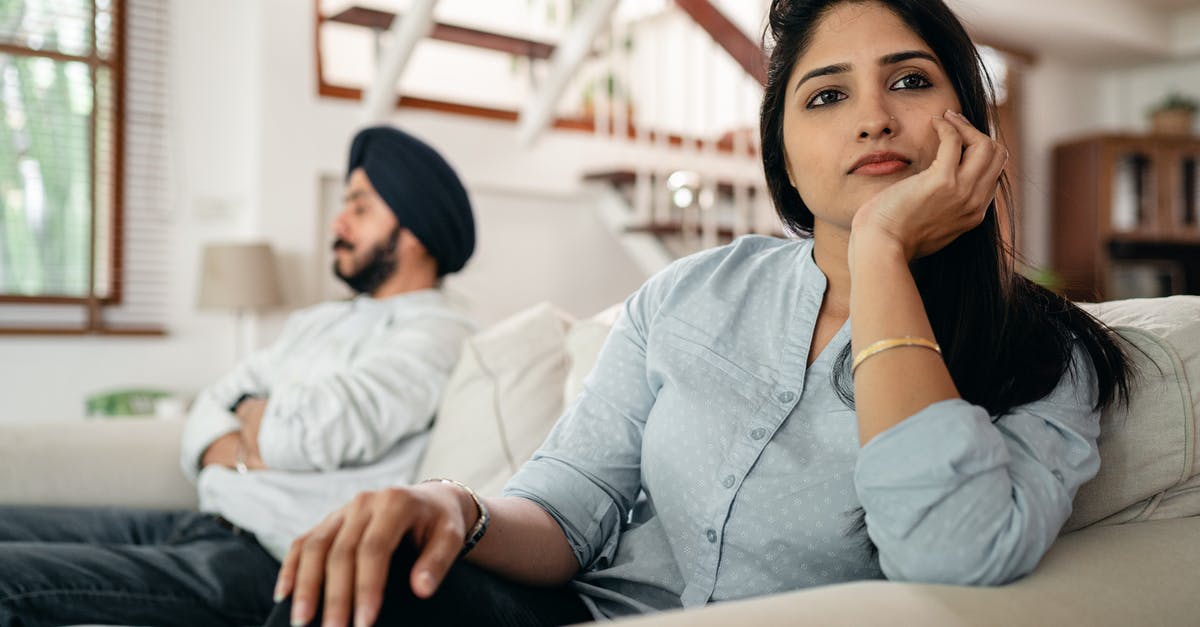 Avoid crumbling pork? - Sad young Indian woman avoiding talking to husband while sitting on sofa