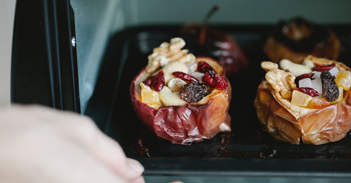 Baked apple that was left out overnight? - Crop unrecognizable chef removing baking sheet with appetizing stuffed baked apples from electric oven at home