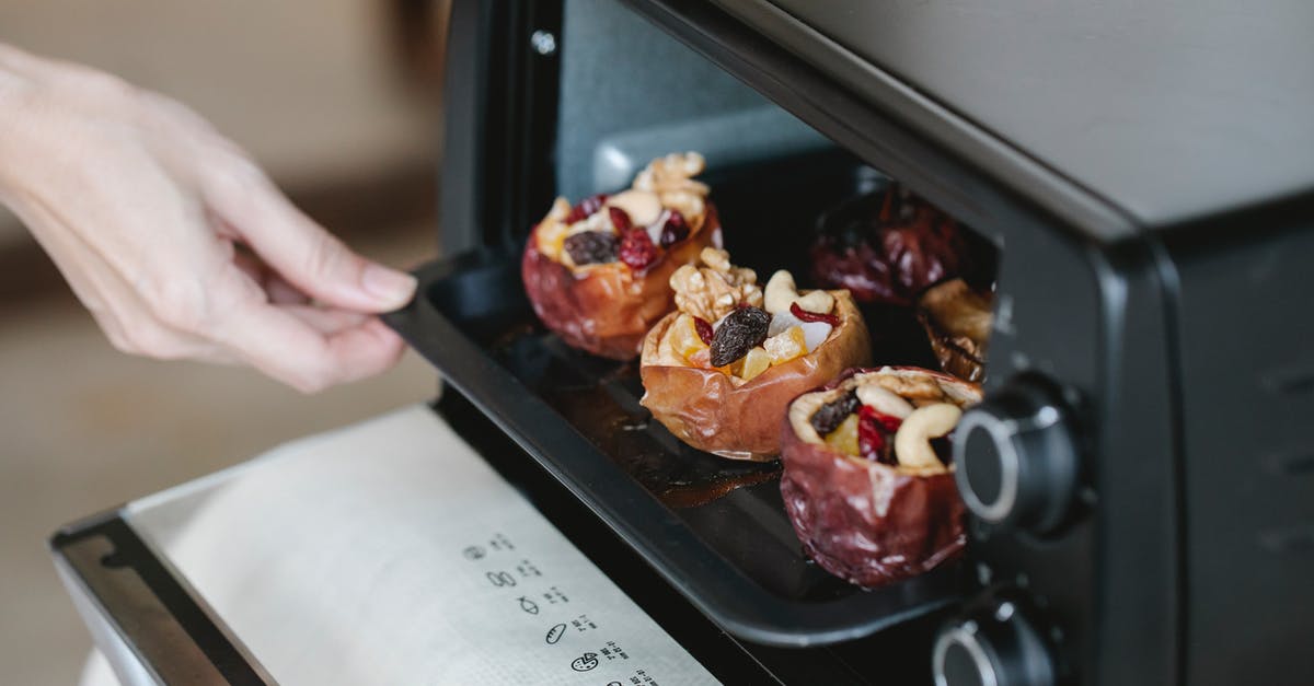 Baked Stuffing and cooking the turkey - Faceless cook getting out baking tray with delicious filled baked apples of electric oven at home