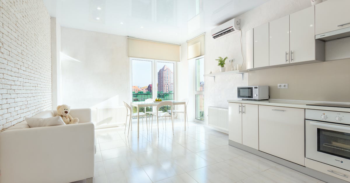 Baking cakes in the Microwave ovens as compared to Electric ovens - Interior of modern house with wooden table and chairs placed near kitchen with white cabinets and appliances