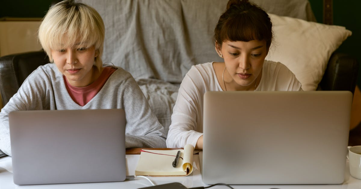 Baking concentrate using Hard Alcohol ex Jack Daniels - Young ethnic female student surfing internet on laptop while sitting near concentrated friend typing on netbook near hard drives and copybook in apartment